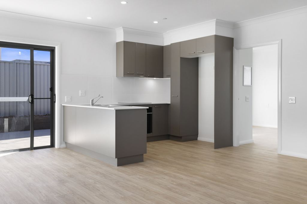Compact kitchen with grey cabinetry and a sliding door to the courtyard.